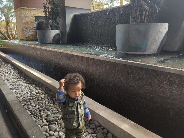 toddler playing near water fountain